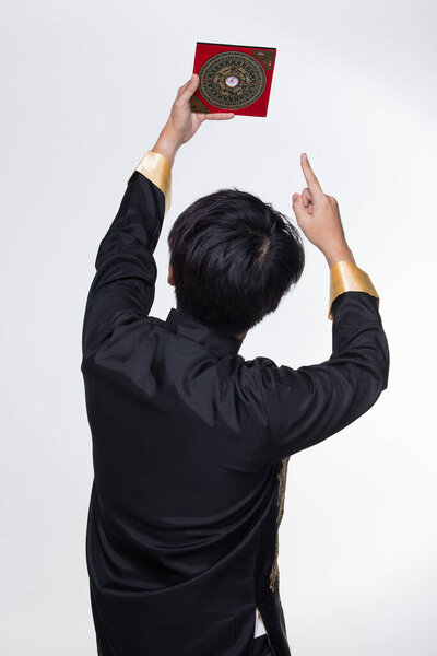 Feng Shui Master show FengShui Compass and turn direction to Force Energy, He wear black shirt to check North South for Luck and Prosperity to Design Building on Wind Water elements Signs, isolated