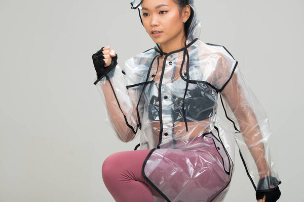 Азиатский Загар кожа фитнес-женщины упражнения растяжения работает разогрев носить спортивные перчатки бюстгальтер прозрачный дождевик моды, студия освещения серый фон копия пространства, концепция Женщина может делать спорт 6 пакетов
