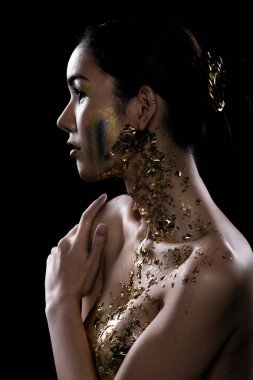 Genç Asyalı Moda Kadını 'nın gözleri siyah, sarılı saçlar güzel makyaj malzemesi göğsünde Altın folyo ya da altın yaprakla süslenmiş. Stüdyo Işıklandırma Karanlık Arkaplan