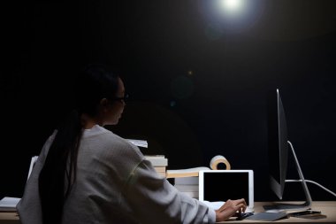 Beyaz tişörtlü Asyalı Kız, masada bir sürü ders kitabı okuyor. Yüksek miktarda yerel ve uluslararası kitap var. Günlük tutanağı.