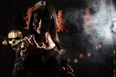 Cadılar Bayramı geçmişinde cadı ve balkabağı çelengi asılı, Yüzünde taze yara olan hayalet zombi kız Yüzünde siyah saç elbisesi korkunç ve tüm perili yerleri öldürmek istiyor