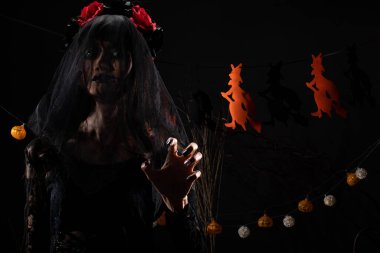 Kara Dul 'un peçesi, yüzü yeni örtünmüş. Yüzünde yeni bir yara izi var. Gölge şeklinde bir siluet.