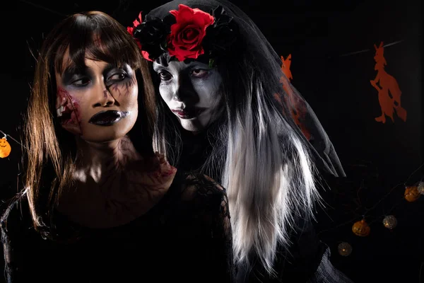 悪魔の白い顔のピエロとゾンビの女の子の黒い髪 魔女とカボチャの頭を持つハロウィンの背景に一緒に所有されている2つの幽霊は ダイツリーを飾る 低キー暗い影露出コピースペース — ストック写真