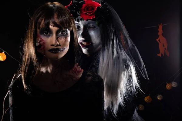 悪魔の白い顔のピエロとゾンビの女の子の黒い髪 魔女とカボチャの頭を持つハロウィンの背景に一緒に所有されている2つの幽霊は ダイツリーを飾る 低キー暗い影露出コピースペース — ストック写真