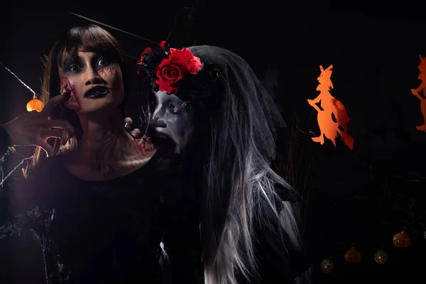 Devil White face clown and Zombie girl black hair, two ghosts possessed together over Halloween backgrounds with witches and pumpkins head decorate die tree, low key dark shadow exposure copy space