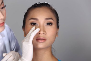 Asyalı Doktor Hemşire estetik ameliyattan önce yüz yapısını kontrol et ve hastaya güzellik kimyasal şırıngası enjekte et.
