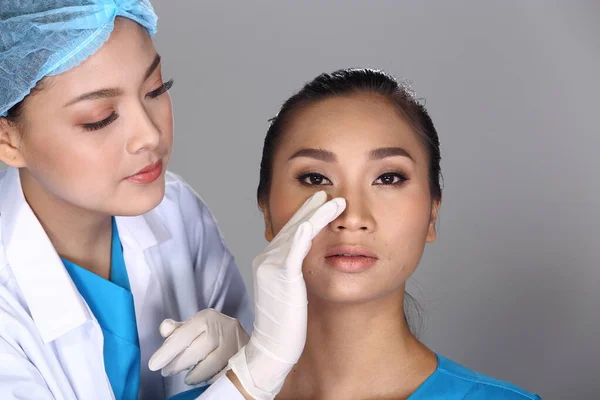 Asian Doctor Nurse check face nose structure before plastic surgery and inject beauty chemical syringe to patient, Studio lighting grey background