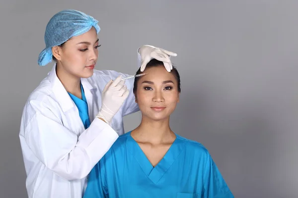 아시아의 간호사는 얼굴의 구조를 확인하고 여드름 사마귀 스튜디오 배경을 환자에게 — 스톡 사진