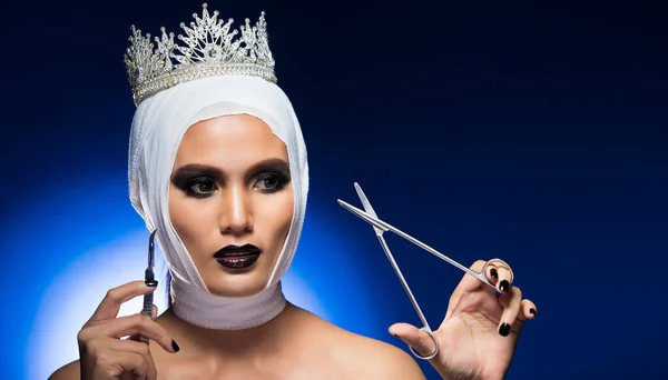 选美比赛的钻石王冠将是最漂亮的女人之后整形手术包扎头部持刀工具 演播室灯光渐变蓝色背景概念宣传高级时尚套装 — 图库照片