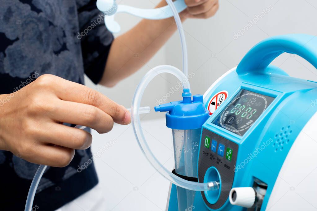 Medical Device Individual Blue White portable oxygen cylinder to put gas for patients with respiratory disorders, woman hand try to plug in the rubber tube to tank