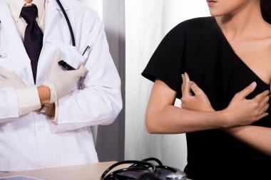 Asyalı Hasta Orta Doğulu Doktor üniformalı kadın tarafından tıbbi hastane kliniğinde steteskopla kontrol edildi. Göğüs kanseri mammografisi veya silikon göğüs implantı konsepti.