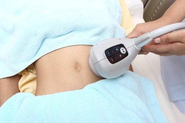 Kadının şişmanlığa karşı sabırlı olması ve hastane kliniğinde karnına uyguladığı tıbbi güzellik aleti ile sorunu incelemesi