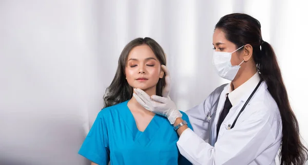 アジアの患者は 整形外科 コピースペースの前に 医療病院のクリニックでのゴム手袋 コンセプトの鼻再生検査と一致してインド中近東の医師の女性によって健康をチェックされました — ストック写真