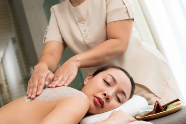 Hafif yeşil bitkisel güzellik tedavisiyle profesyonel terapist. Beyaz ırk, beyaz Asyalı kadın derisi. Sağlık kaplıcasında, eskisini fırçalayarak yeni ve pürüzsüz bir cilt için.