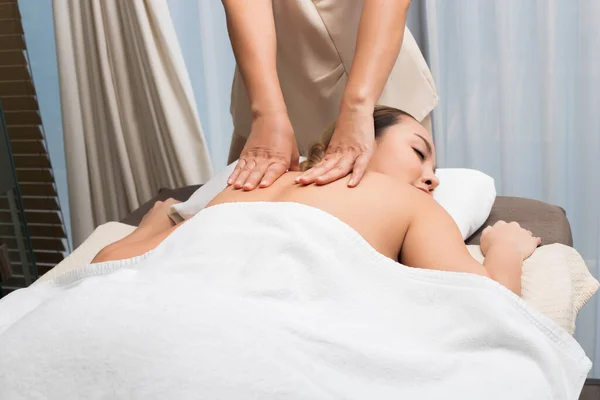 Body Massage on specific naked back of Mix Race Caucasian Asian woman by pressing fingers on pain or stress muscle point to release relax.  Therapist Spa body massage woman hands treatment on customer