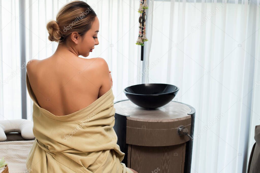Beautiful Mix races Caucasian Asian woman feel good after Thai body Massage oil therapy scrub and treatment, wearing rob sitting in massage room with windows