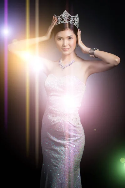 Portrait of Miss Pageant Beauty Contest in sequin Evening Ball Gown long dress with sparkle light Diamond Crown, Asian Woman fashion make up black hair style, studio lighting dark background dramatic