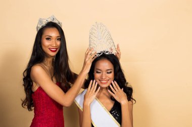 İki Güzellik Yarışması Güzellik Kraliçesi Yarışması 'nın Asya Akşam Balosu pul pul elbisesi ve Diamond Crown Sash' ı giymesi beklenen son an. Tacı kazanan oturuma koymak ve el ele tutuşmak.