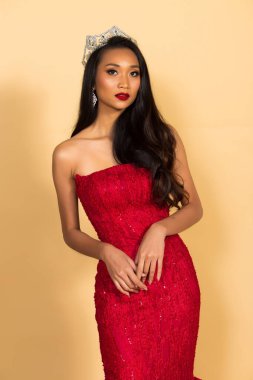 Asya Güzellik Yarışması Kraliçesi. Gece Balosu elbisesi, elmas taç kuşağı, makyaj, yüz makyajı, kalp saç stili, stüdyo ışıklandırması bej arka plan izole edilmiş kopya alanı.