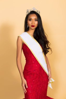 Asya Güzellik Yarışması Kraliçesi. Gece Balosu elbisesi, elmas taç kuşağı, makyaj, yüz makyajı, kalp saç stili, stüdyo ışıklandırması bej arka plan izole edilmiş kopya alanı.