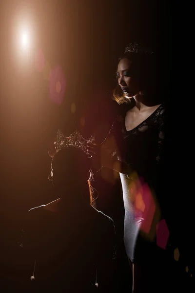 二つのシルエット影バックリム光のミスペガントビューティークイーンコンテストは 上のシルバーダイヤモンドクラウンを置きます受賞者の最後の瞬間世界で最も美しい女性 スタジオ照明暗い黒の背景 — ストック写真
