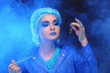 Mavi Ton Moda Bilimadamı Karanlık Oda Laboratuvarında aletlerle laboratuvar hijyeni, damlatıcı, cam tüp, şırınga, dijital tablet, stüdyo ışıklandırması, dumanlı siyah koyu arkaplan