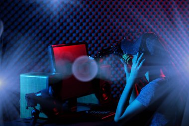 Genç Yetişkin Youtube 'da bir cover şarkısı söylüyor. Kadın sosyal medyayı elektronik oyun klavyesi, fare, monitör, hoparlör, kamera, stüdyo, koyu kırmızı tema gibi profesyonel ekipmanlara bağlıyor