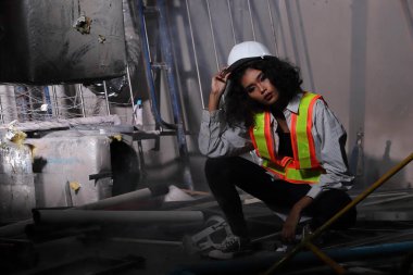 Güzel Asyalı mimar kadın beyaz başlıklı kıvırcık saçlı, inşaat odasındaki büyük güvenlik enkazı temizliyor ve yenileme yapıyor, konsept kadın moda sonrası sahne yapabilir.