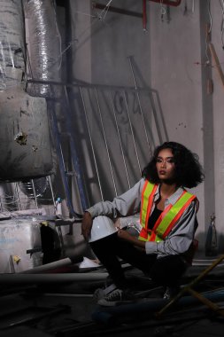 Güzel Asyalı mimar kadın beyaz başlıklı kıvırcık saçlı, inşaat odasındaki büyük güvenlik enkazı temizliyor ve yenileme yapıyor, konsept kadın moda sonrası sahne yapabilir.