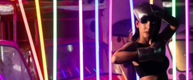 Güzel 20 'li yaşlarda Asyalı transseksüel kadın trenleri gümüş eldiven giyer. Modern çok renkli Neon Muay Tai Boks Salonu arka planında spor sporu