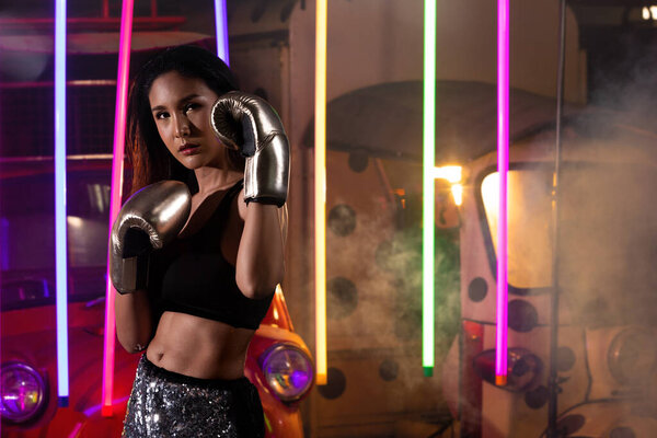 Красивые 20-х азиатские трансгендеры Женщина тренируется серьезно удар на серебряные перчатки моды Миттс. Спортивные упражнения спортсмен на современном многоцветный неон Муай Тай Бокс фоне в поту
