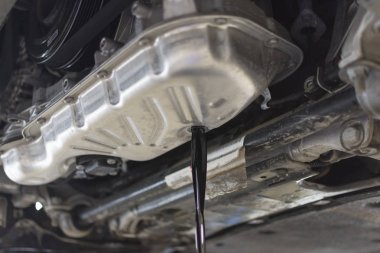 The old oil is drained from the car engine. Car maintenance. The car engine is bottom view. Oil change in the engine. Car service.