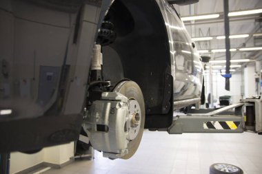 The car on the lift prepared to repair. Details of the brake system. Background interior repair shop.