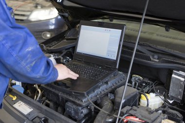Profesyonel tamirci araba servisindeki bir arabaya teşhis koyuyor. Bir arabanın elektriksel tanıları.