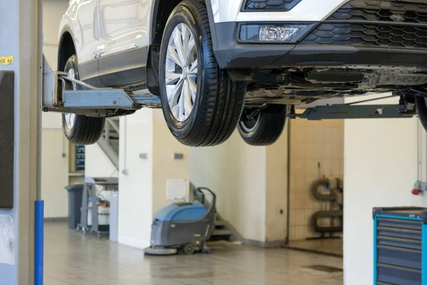 A car on a lift in a car service is raised for repair. Car on the background of a service station.