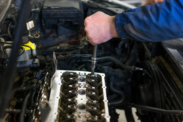 分解された車のエンジンの背景にツールを保持しているプロの整備士の手 車のエンジンの修理 — ストック写真