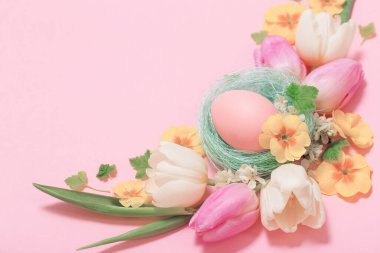 Pembe arka planda Paskalya yumurtaları ve bahar çiçekleri 