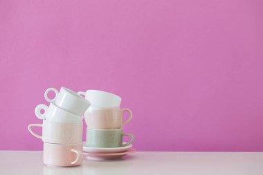 Arkadaki pembe duvardaki beyaz masada modern bardaklar