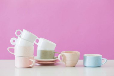 Arkadaki pembe duvardaki beyaz masada modern bardaklar