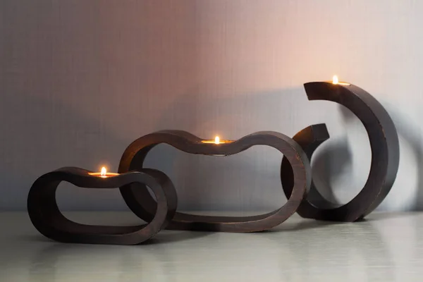 Burning candles in dark wooden candlesticks on white table — 图库照片