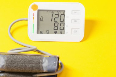 modern tonometer on yellow background, pressure 120 to 80 on  mo