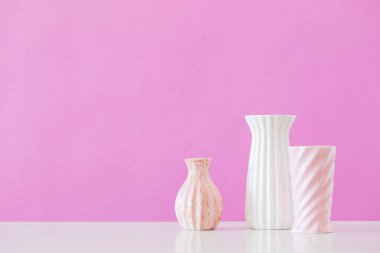 Pembe arka planda beyaz ve pembe vazolar