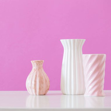 Pembe arka planda beyaz ve pembe vazolar