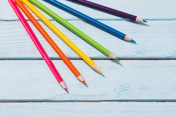 six-color rainbow from pencils on blue wooden background