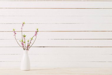 Vazodaki Daphne çiçekleri beyaz ahşap arka planda