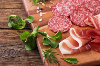 Ahşap masada çeşitli et ve sosisler var.