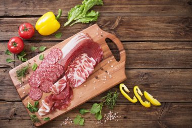 Tahta masada çeşitli et ve sebzeler var.