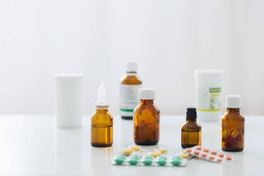 İlaç şişesi beyaz arka plandaki masada.