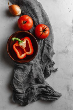 Sebzeli ahşap tabak, domates, biber, açık beton arka planda kumaşlı soğan.
