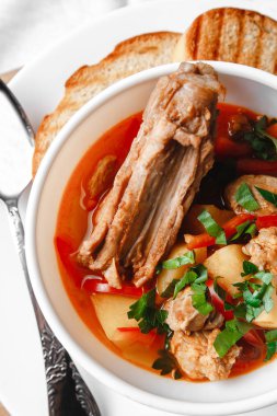 Fasulyeli çorba ve beyaz tabakta ekmekli et.